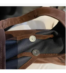 Detail of round magnetic closure and matte brown texture on large shoulder tote bag