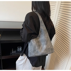 Close-up of the dark grey suede shoulder bag featuring a silver snap closure and wide strap