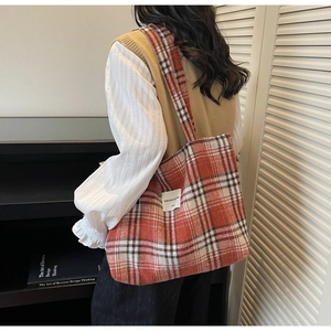 Detail of red and white checkered tote bag in textured wool worn on the shoulder