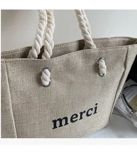 Close-up of linen tote bag with rope handles and black merci text detail