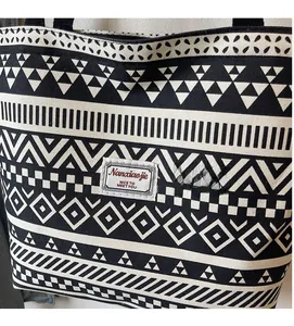 Close-up of a thick canvas tote bag featuring black and white geometric pattern and a label