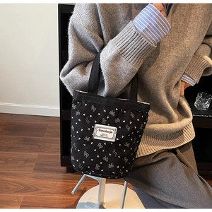 Close-up of black corduroy tote bag featuring white bow patterns and heart prints