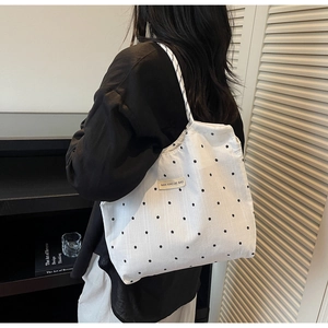 Detail view of white mesh tote bag with black floral pattern and woven label logo