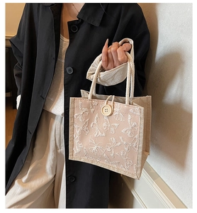 Detail of small canvas bag featuring white butterfly applique and cotton rope handle