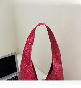 Detailed close-up of wide handles and crocodile leather texture on the tote bag