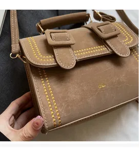 Nahaufnahme der braunen Umhängetasche mit Vintage-Textur und gelben Zickzack-Stickereien