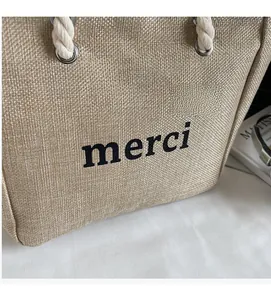 Detailed texture of beige linen bucket tote bag featuring black merci print and cotton rope