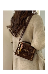 Detail of vintage leopard print crossbody bag with gold studs and ethnic beaded charm