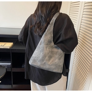 Detail of dark gray suede shoulder bag featuring a silver metal rivet and textured finish