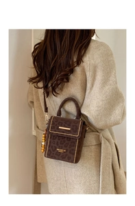 Detail of leopard print crossbody bag featuring gold rivets and beaded pendant accents