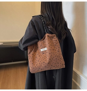Close-up of brown corduroy tote bag with black bow print and woven rope shoulder strap