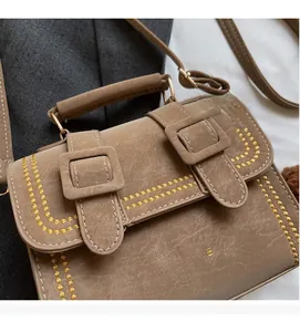 Details einer braunen Vintage-Umhängetasche mit gelber Stickerei und Goldbeschlägen