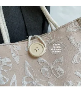 Detail of butterfly embroidery on pink canvas bag with wooden button closure