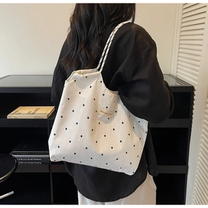 Detail of white mesh tote bag with black floral print and drawstring closure