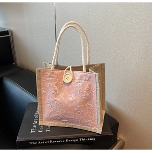 Detail of linen tote bag with 3D floral embroidery and button closure on fabric
