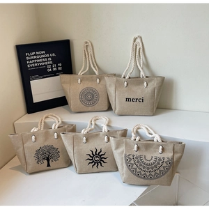 Detailed macro view of five linen tote bags with cotton rope handles and diverse patterns