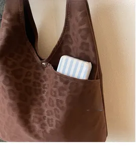 Detail of leopard print tote bag featuring a functional front pocket and matte suede texture