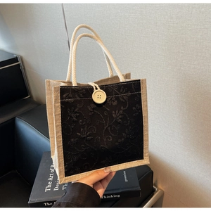 Close-up of linen tote bag with black floral embroidery and white cotton rope handles
