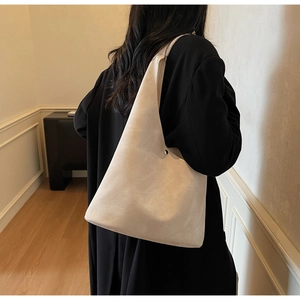 Detail of oatmeal suede tote bag with silver circular buckle on a black wool coat