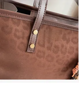 Close-up of leopard embossed suede tote with gold studs and beaded charm detail