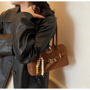 Detail of brown suede shoulder bag with decorative beads and metallic eyelet strap
