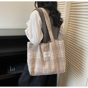 Detail view of beige plaid tote bag showing thick textured fabric and stitched logo patch