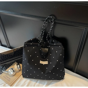 Detail of black floral tote bag with woven handles showing texture and spacious capacity