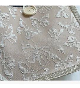 Close-up of beige canvas lunch bag with elegant white butterfly embroidery detail