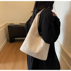Detail view of large capacity beige tote bag in soft suede shown on female model