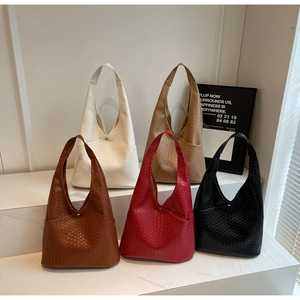 Close-up of five woven tote bags in assorted colors featuring minimalist textured design