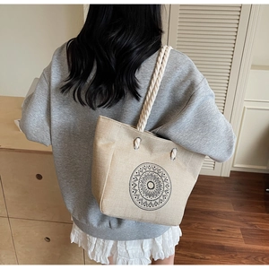 Detail of linen tote bag featuring a black mandala pattern and braided rope handle