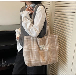 Detail of large beige checkered tote bag showing woven fabric texture and logo patch