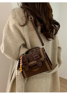 Detail view of brown leopard print crossbody bag with metal rivets and beaded charm
