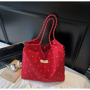 Detail of red floral tote bag with white flower patterns and woven rope handles