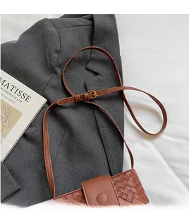 Detail of woven brown bucket bag with adjustable strap over a stylish grey blazer