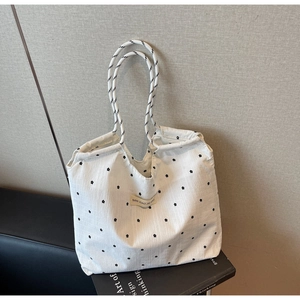 Detail of floral canvas tote bag with woven rope handles and a minimal logo patch