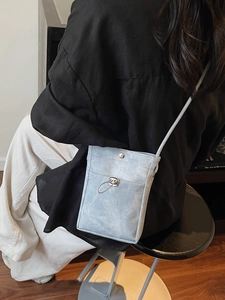 Sac à bandoulière minimaliste bleu clair en toile porté par un modèle en intérieur