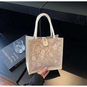 Detail of beige linen tote bag featuring 3D floral embroidery and cotton rope handles