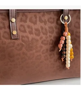 Close-up of leopard print tote bag fabric with wooden bead tassel and rivet detail