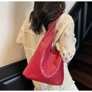 Detailed view of red woven leather hobo bag worn by a model in a minimalist setting
