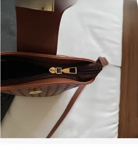 Detailed macro view of the smooth golden zipper and magnetic clasp on the brown bucket bag