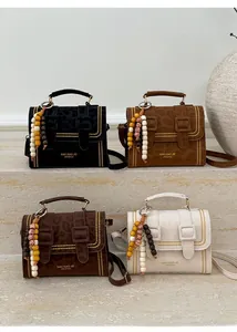 Detail of suede crossbody bags with gold rivets and tassel charms in four colors