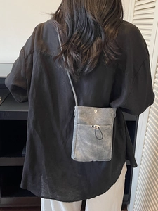 Petit sac de téléphone en toile grise avec cordon porté sur une chemise en lin noir