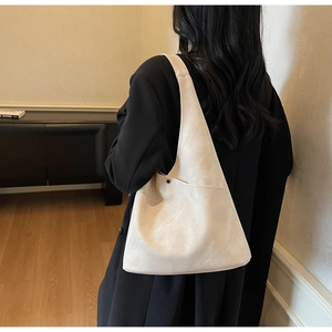 Detail of minimalist beige faux suede bucket bag shown in a warm indoor lifestyle setting