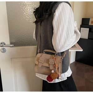 Nahaufnahme der khakifarbenen Cambridge-Tasche mit Schnallen und Plüsch-Anhänger