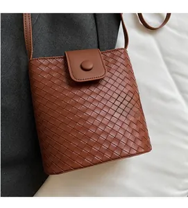 Detail of brown woven leather texture and magnetic flap closure on stylish bucket bag