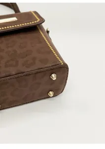 Close-up of leopard pattern suede bag with gold rivets and metallic bottom studs