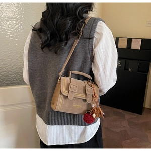 Braune Vintage-Satteltasche mit Goldnieten, Zierriemen und rotem Plüsch-Schlüsselanhänger