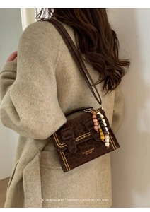 Detail of leopard print crossbody bag with gold studs and beaded charm on model