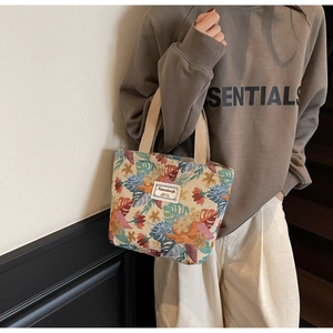 Detail of colorful tropical palm leaf embroidery and beige canvas handle on a tote bag
